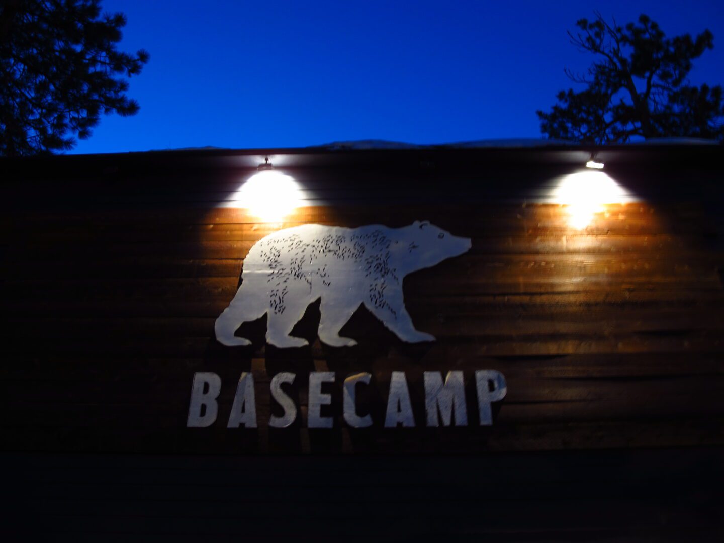 A sign that says basecamp is lit up at night.