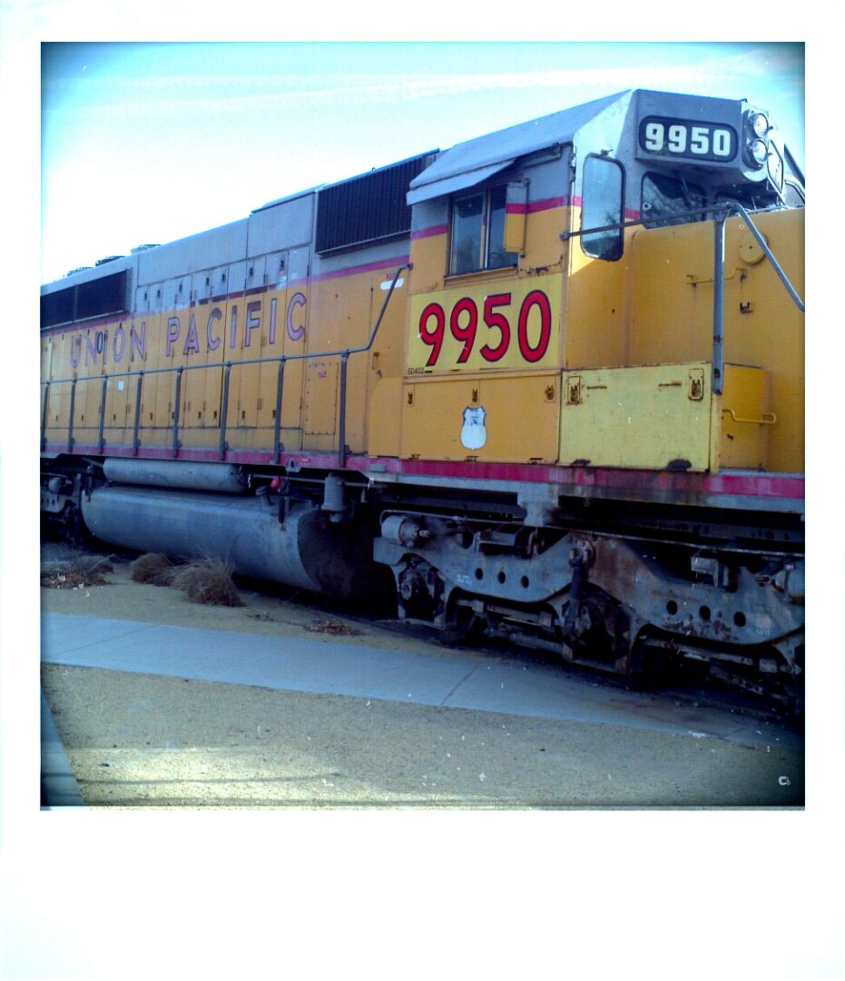 A yellow and black train on the tracks.