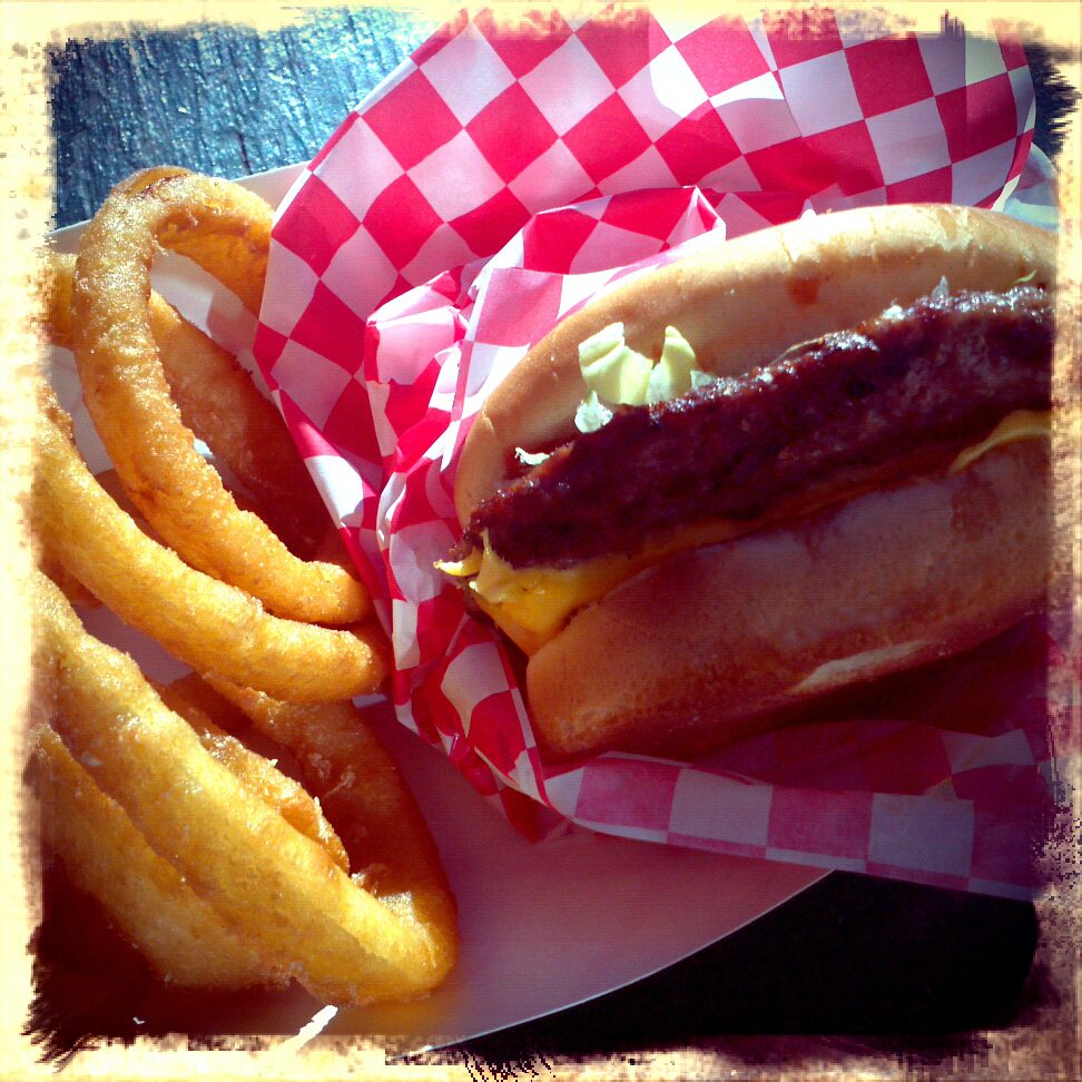 A hamburger and onion rings on a plate.