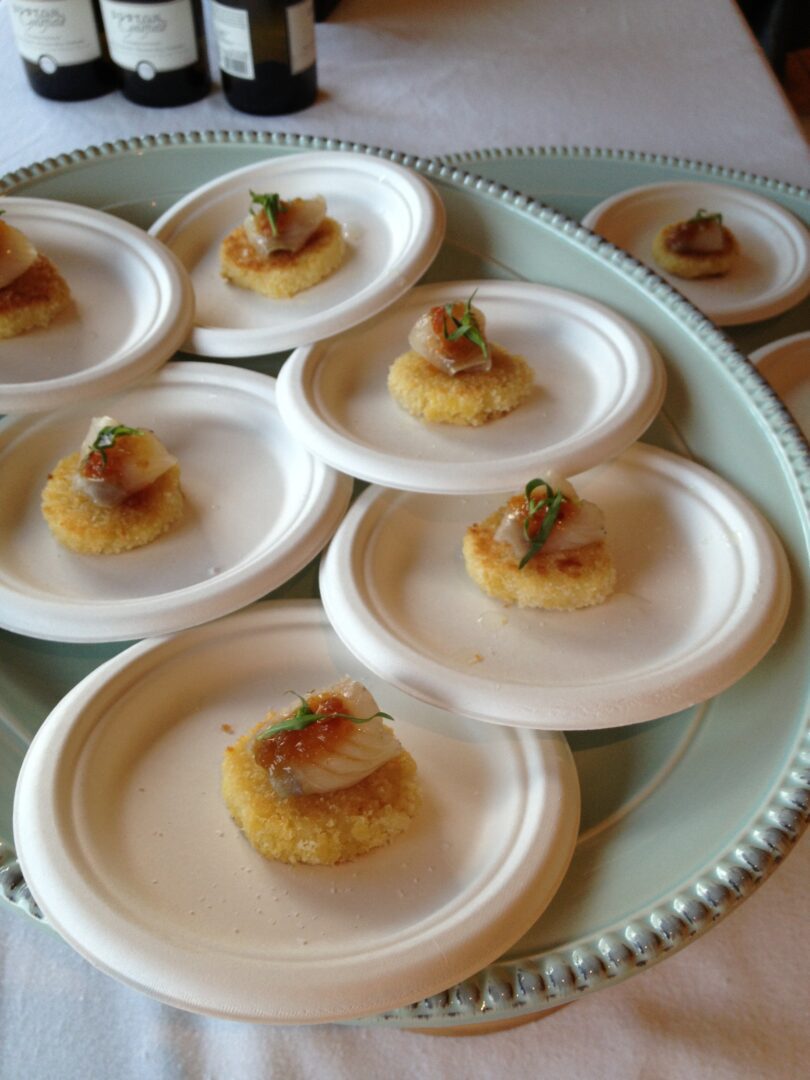 A plate of appetizers on a table next to a bottle of wine.