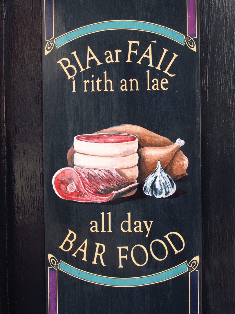 A wooden sign that says bia ar fail i rith an lae all bar food.