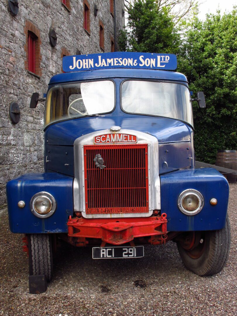 A blue truck parked in front of a brick building.