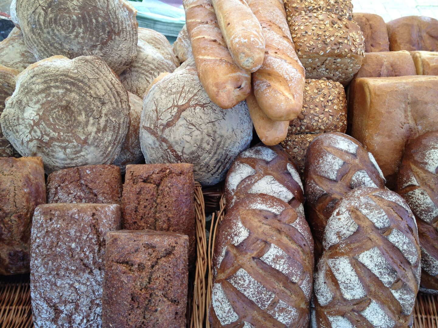 A variety of breads are on display in a wicker basket.