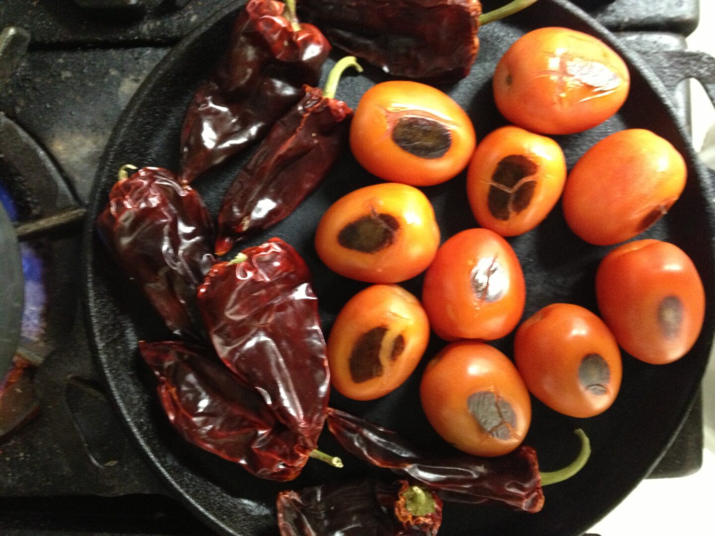 A frying pan with tomatoes and peppers on it.