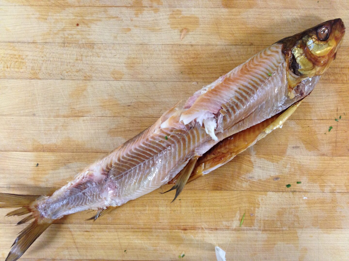 A fish is sitting on a cutting board.