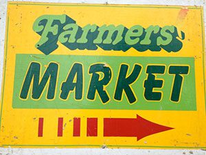 A farmer's market sign with an arrow pointing to the right.