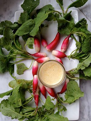 Radishes on a white plate with a sauce.