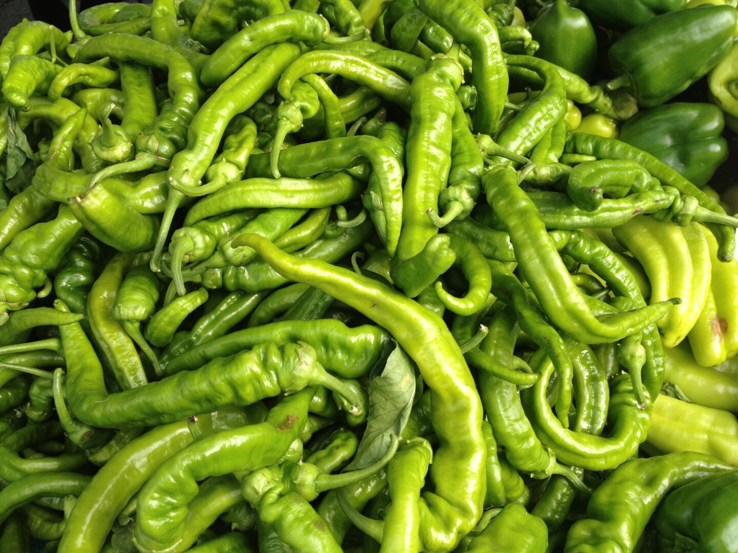 A pile of green peppers on a table.