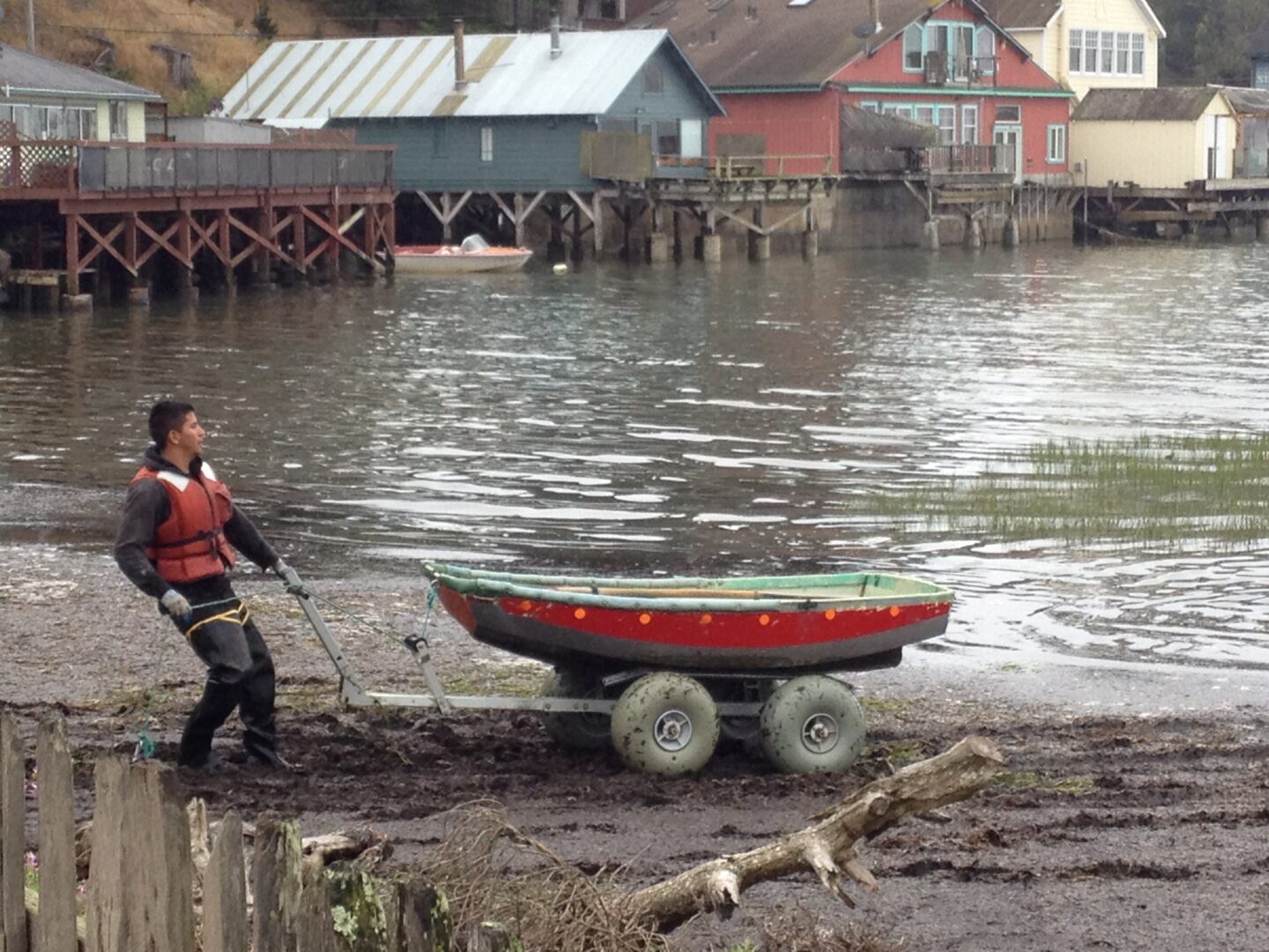 A man pushing a boat in the mud.