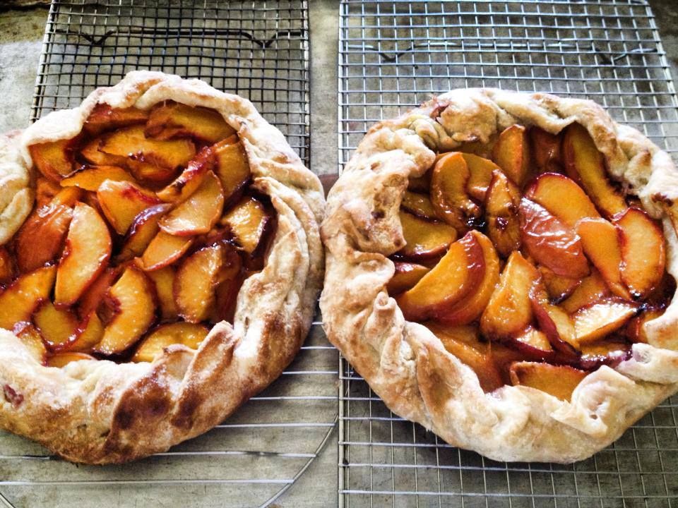 Two peach tarts on a cooling rack.