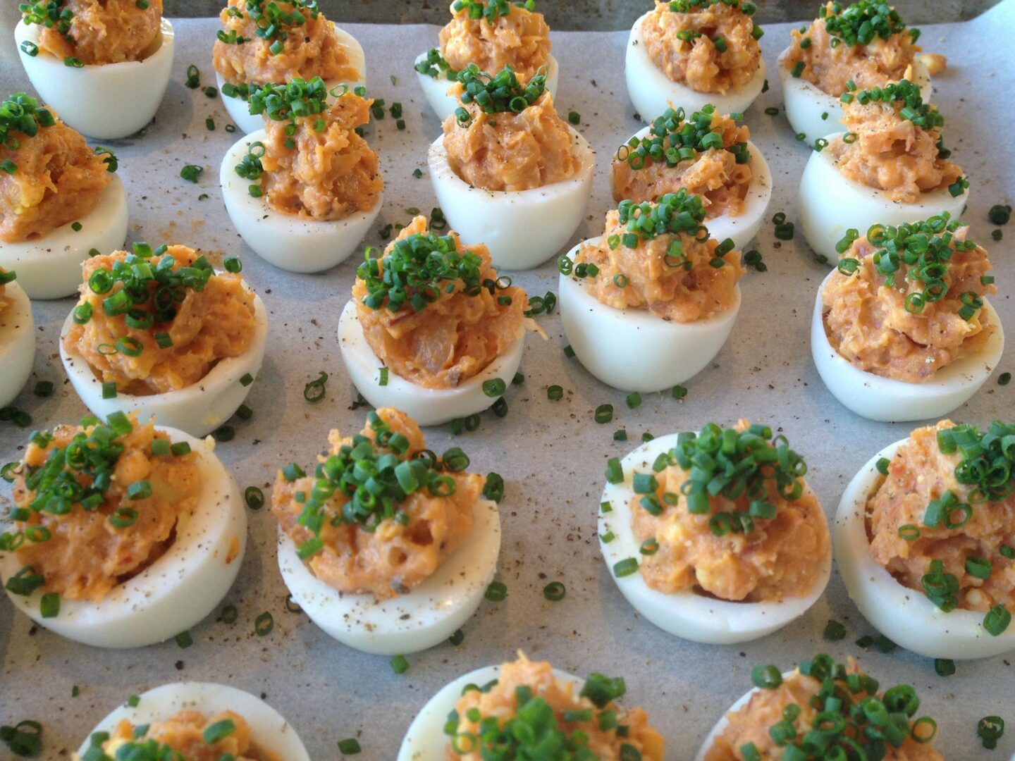 Deviled eggs on a baking sheet with chives.