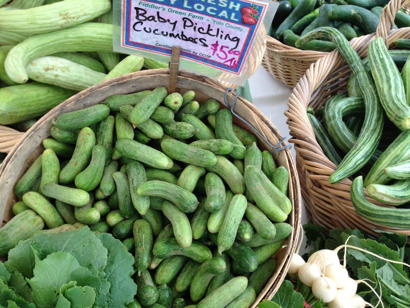 A bunch of cucumbers in baskets on a table.