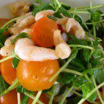 A white plate with shrimp, tomatoes and greens.