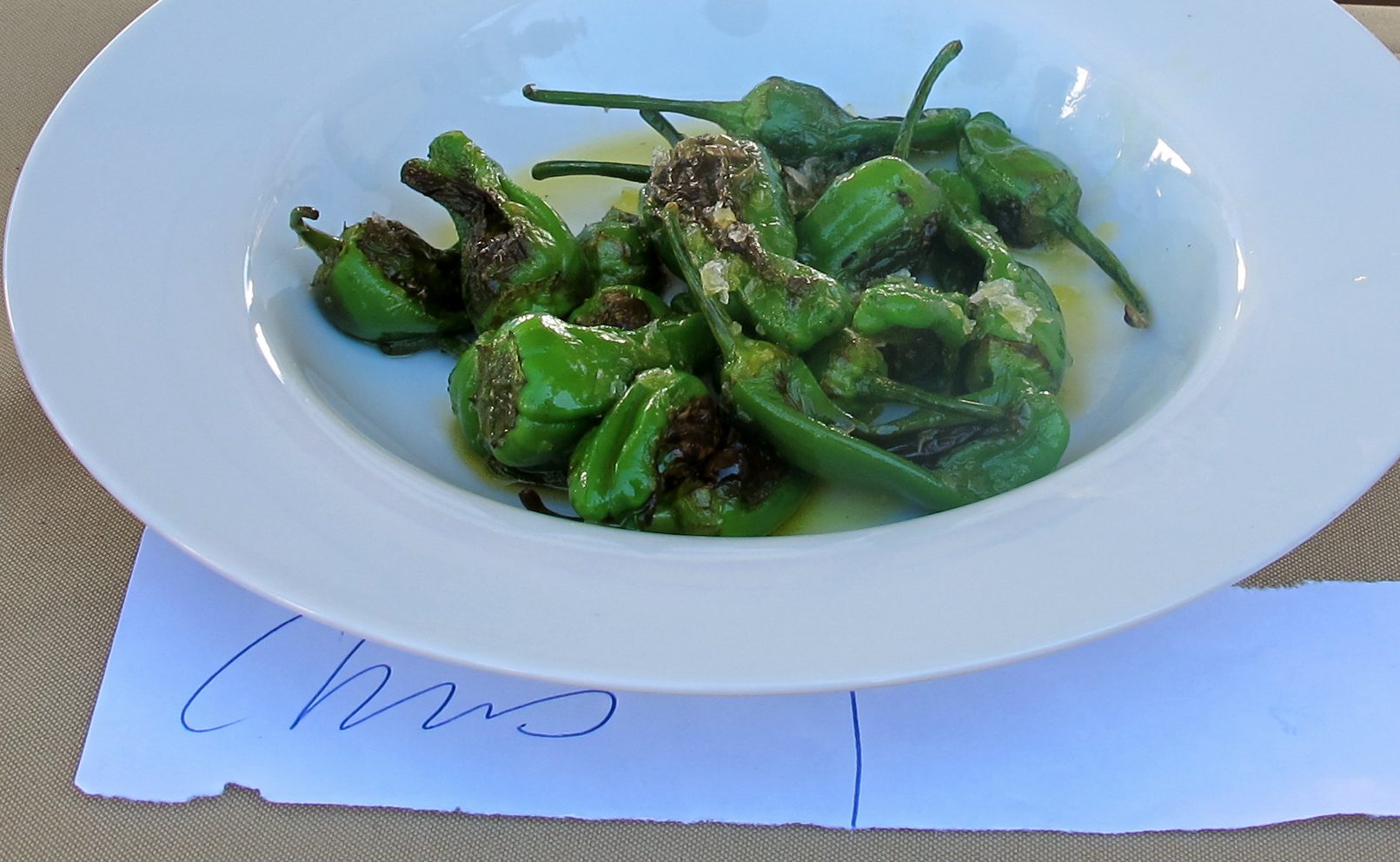A bowl of green peppers with a note on it.