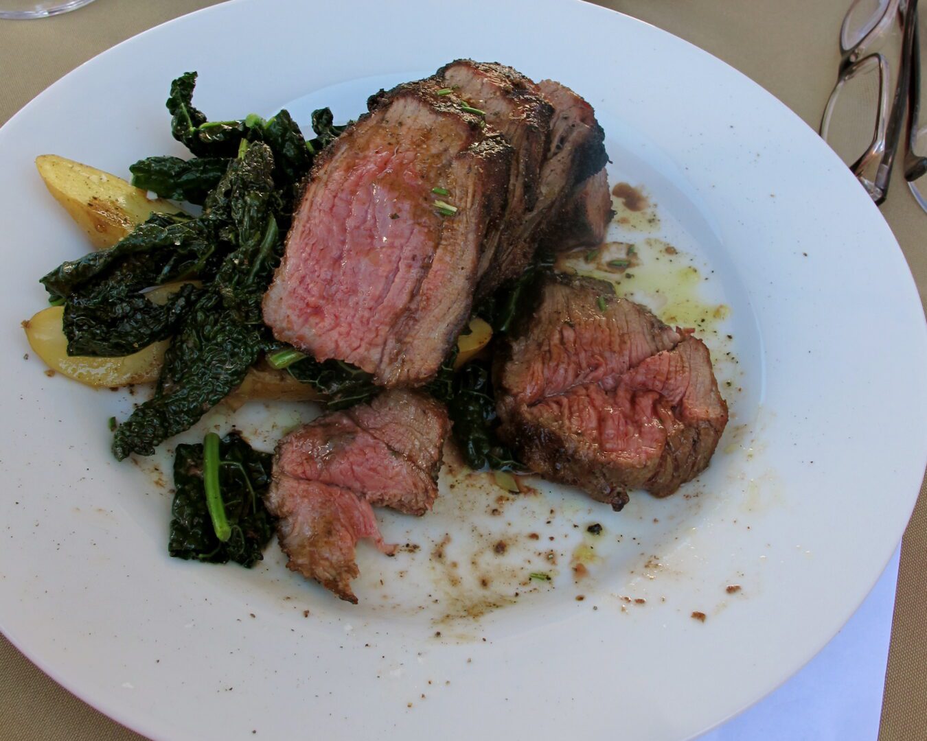 A plate of steak and greens on a table.