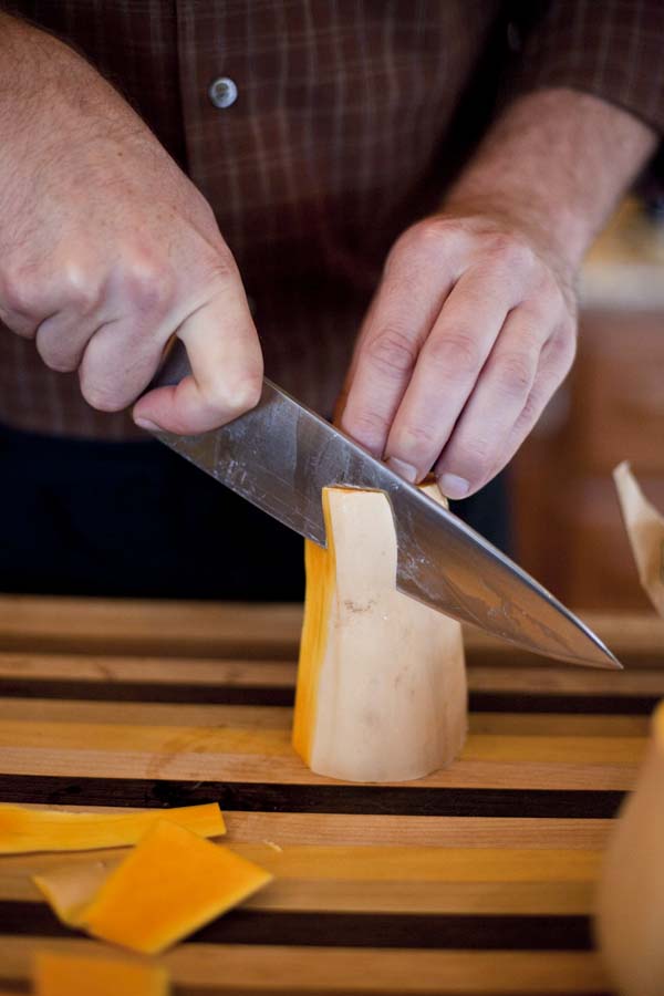 A man cutting a piece of cheese on a cutting board.