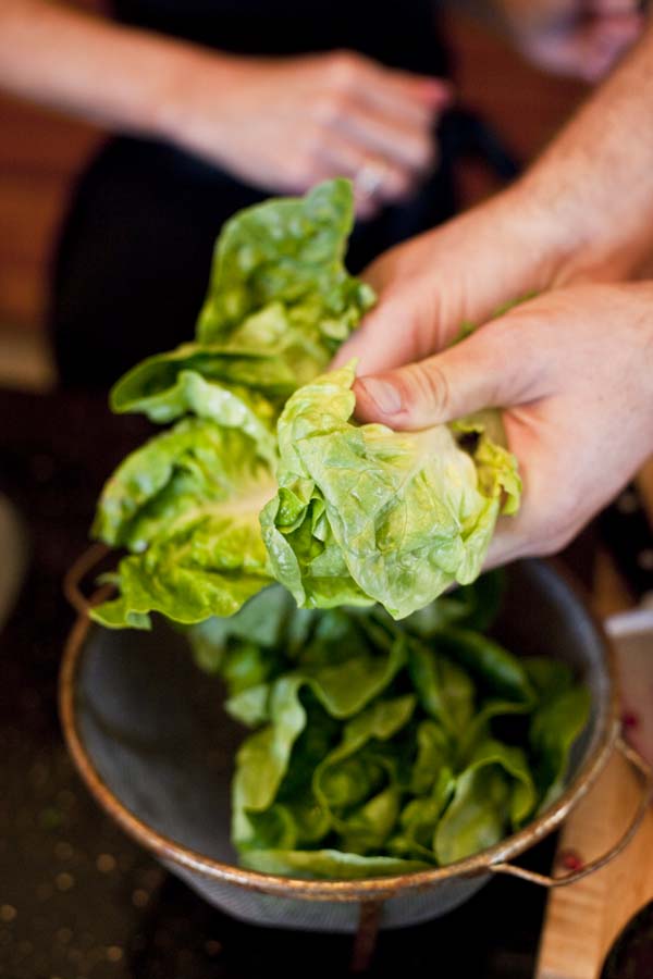 A person putting lettuce into a bowl.