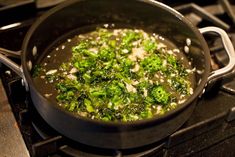 A pot of broccoli cooking on top of a stove.
