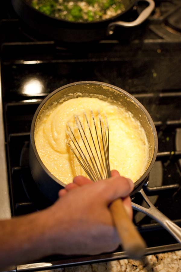 A person is whisking something in a pan on a stove.