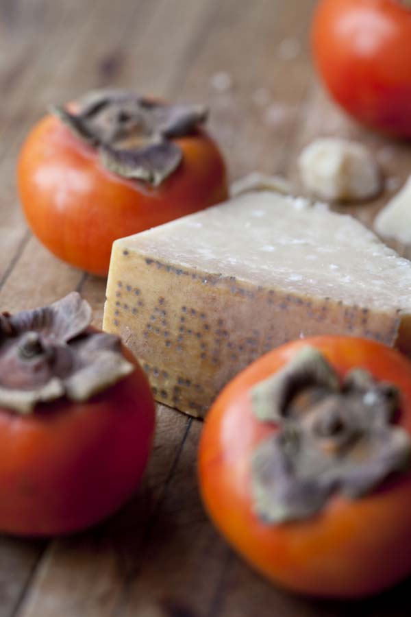 Persimmons and cheese on a wooden table.