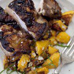 A plate with grilled pork chops and squash.