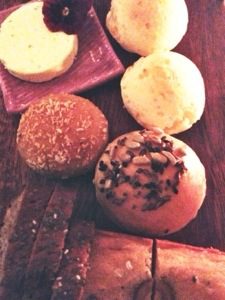 A plate of breads and pastries on a wooden table.