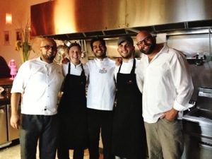 A group of chefs posing for a photo in a kitchen.