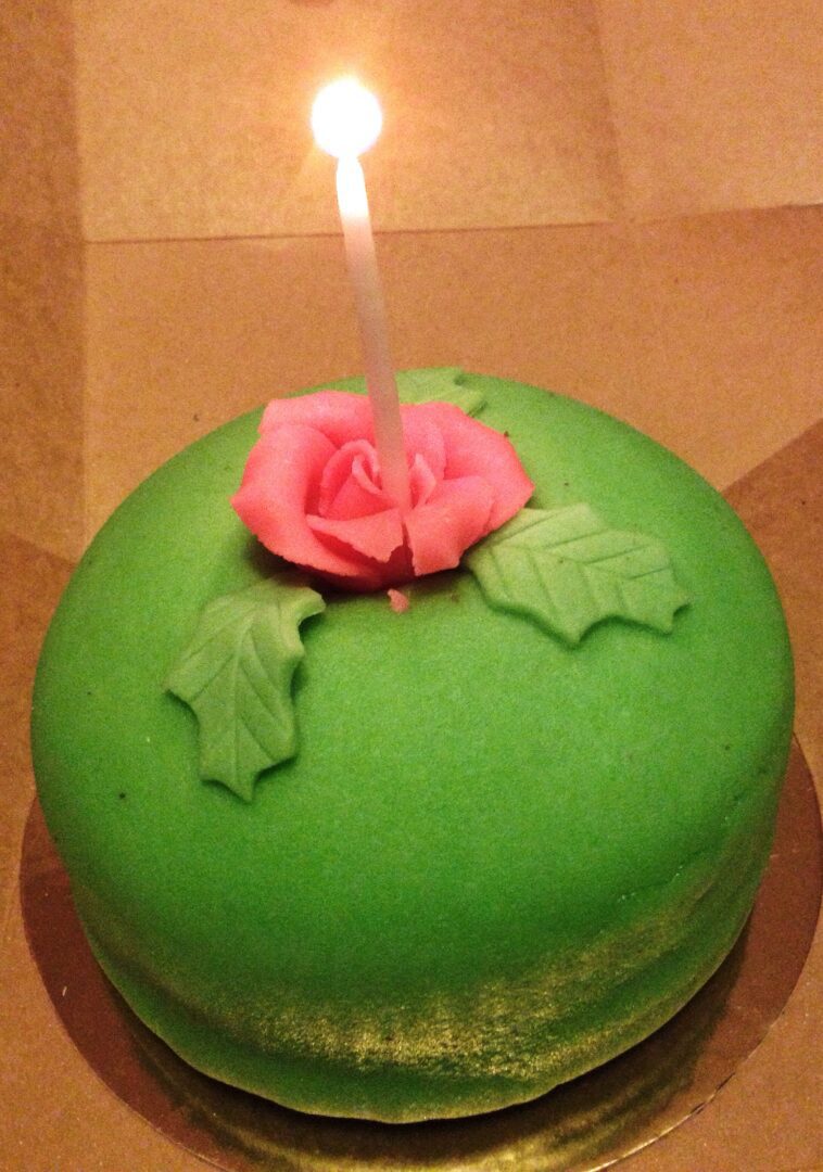 A green cake with a candle on top.