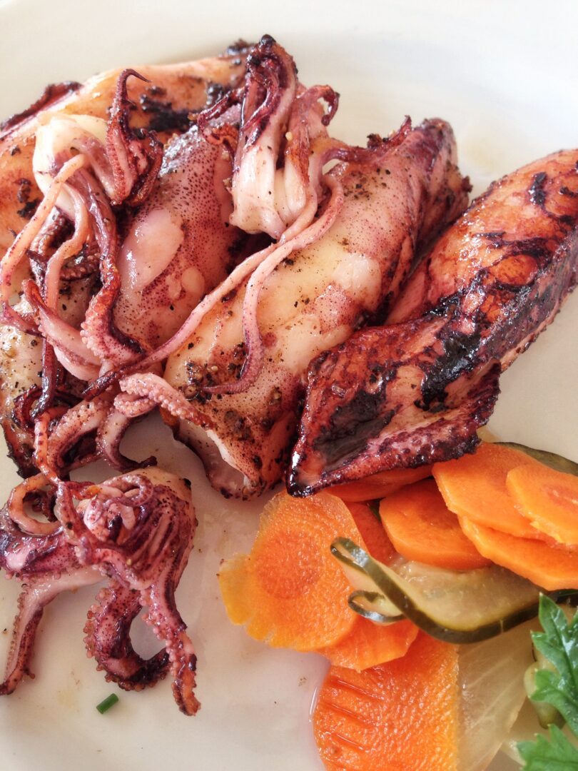 A plate of grilled octopus and vegetables.