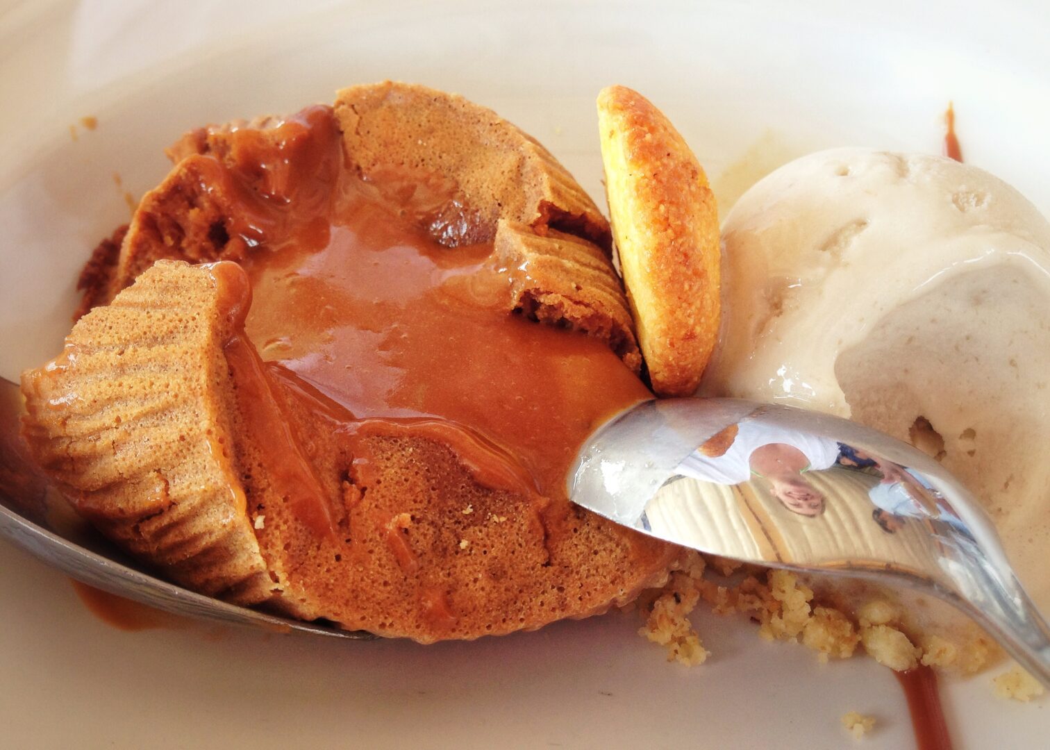 A dessert with ice cream and caramel on a white plate.