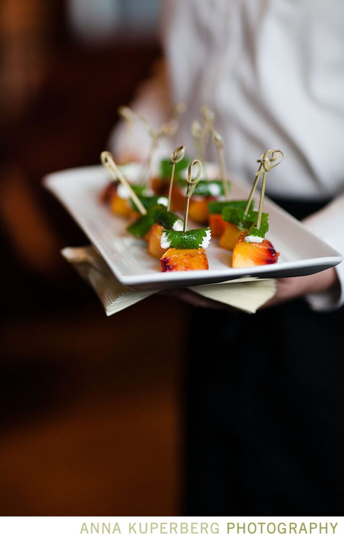 A waiter is holding a plate of appetizers.