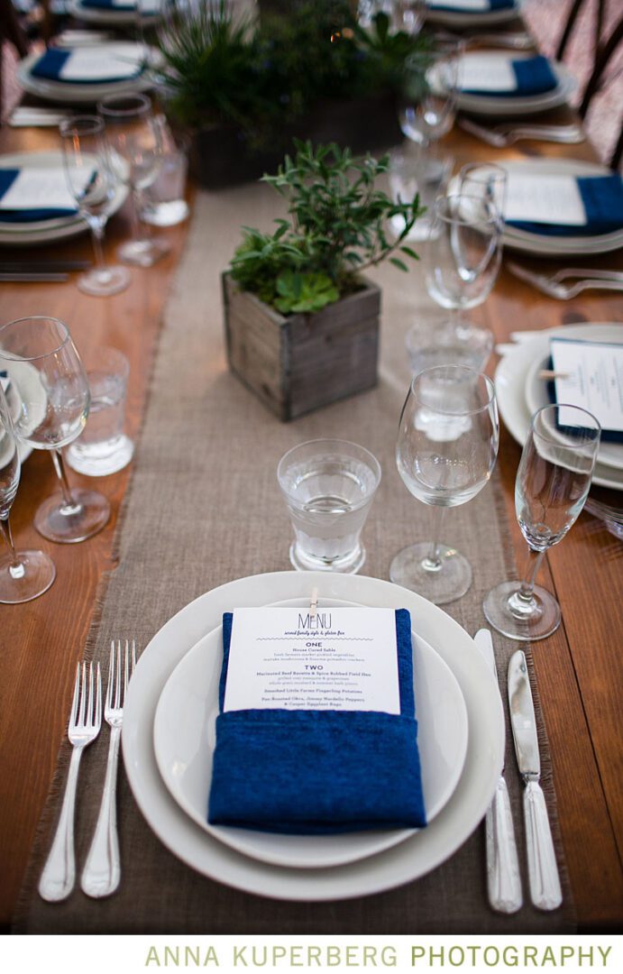 A table setting with blue napkins and silverware.