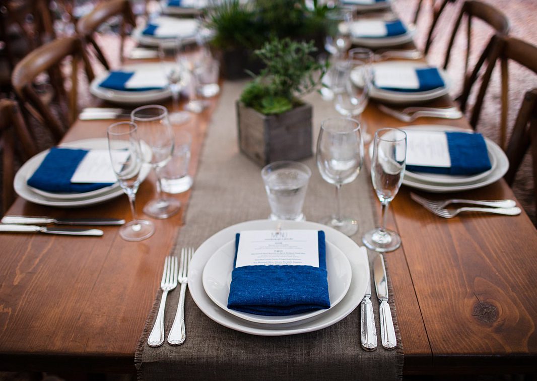 A table setting with blue napkins and silverware.