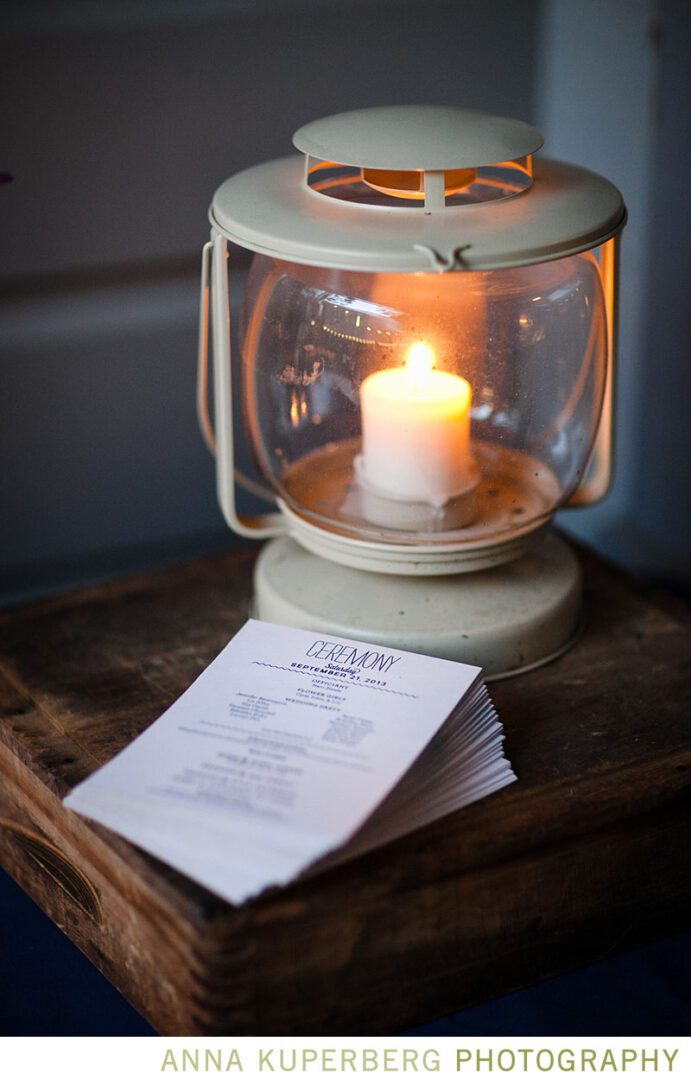 A lantern sits on top of a table next to a wedding program.