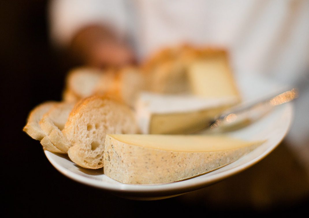 A person is holding a plate of bread and cheese.