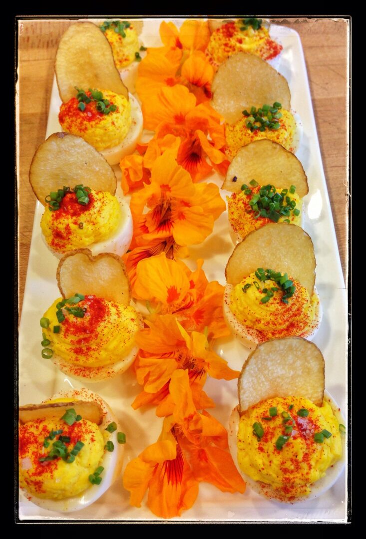 Deviled eggs on a white plate with orange flowers.