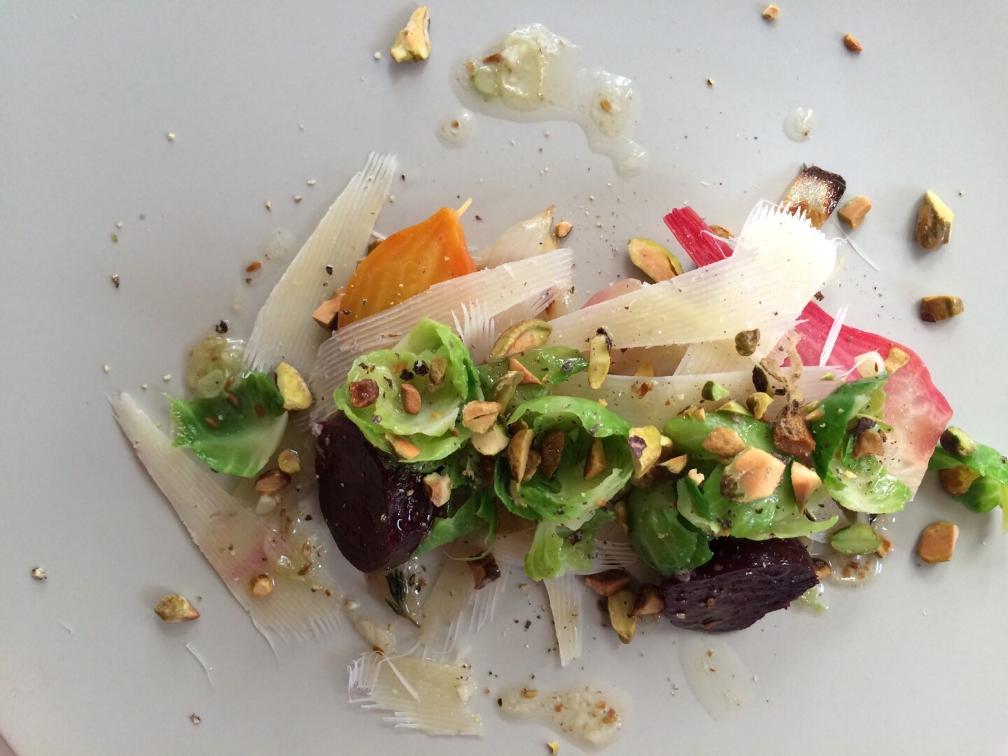 A white plate with beets and nuts on it.