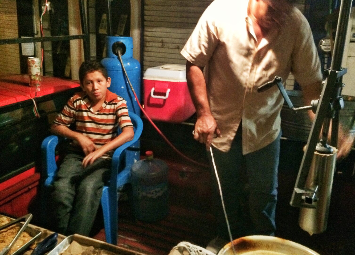 A man and a boy cooking food on a boat.