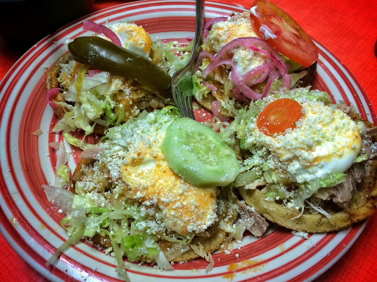 A plate of tacos on a red and white tablecloth.