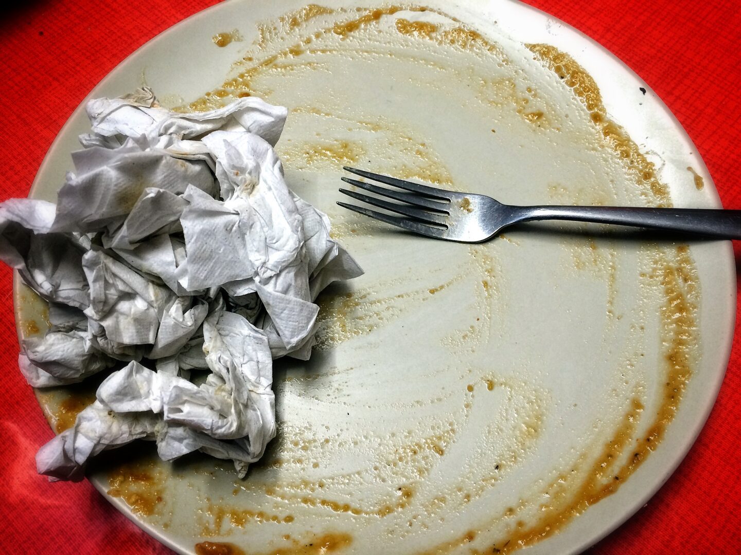 A plate with a fork and a piece of paper.