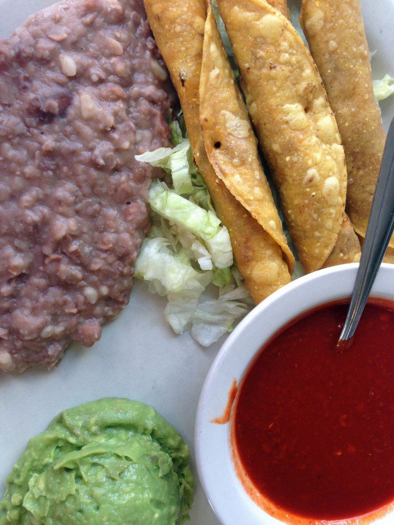 A plate of food with guacamole and tortillas.