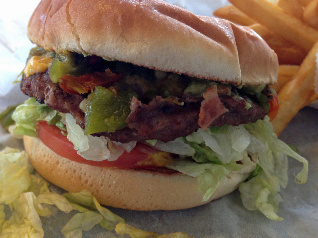 A hamburger on a bun with lettuce and tomatoes.