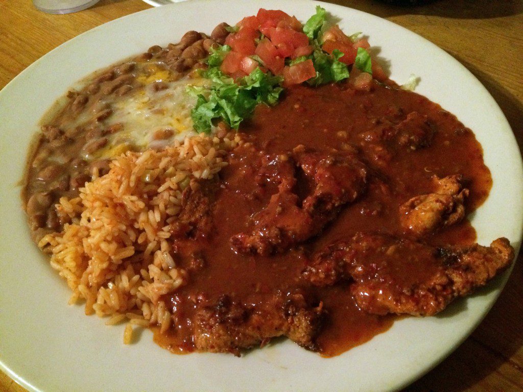 A plate with chicken, rice and beans on it.