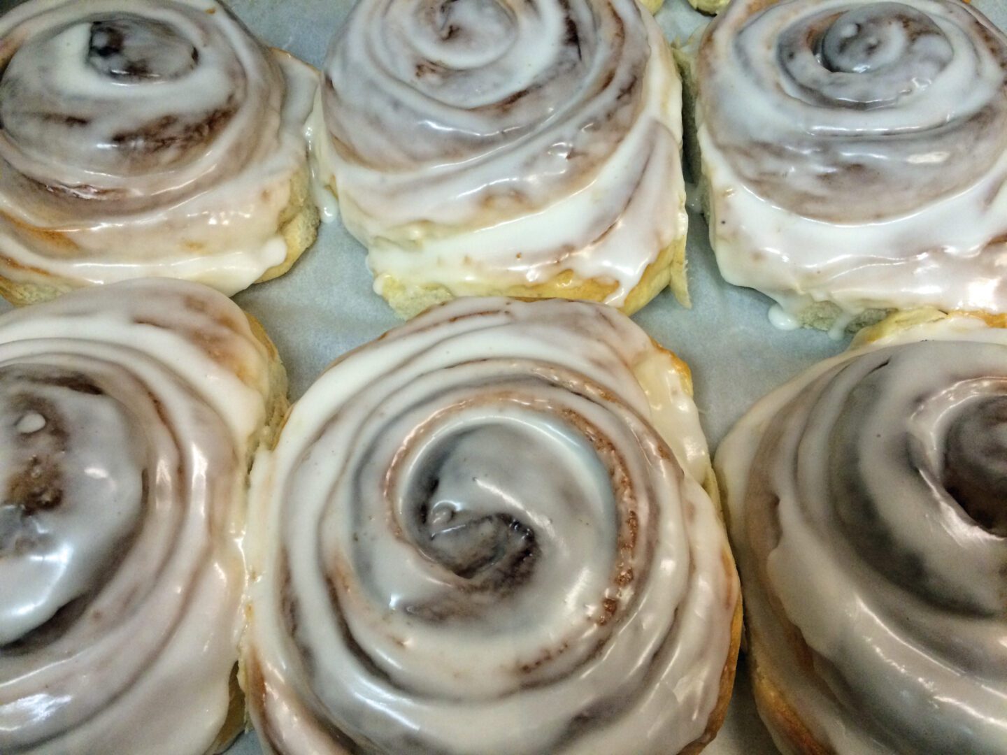 Cinnamon rolls with icing on a baking sheet.