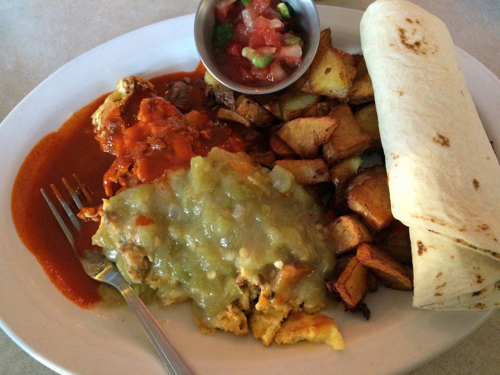 A plate with a burrito, eggs and potatoes.