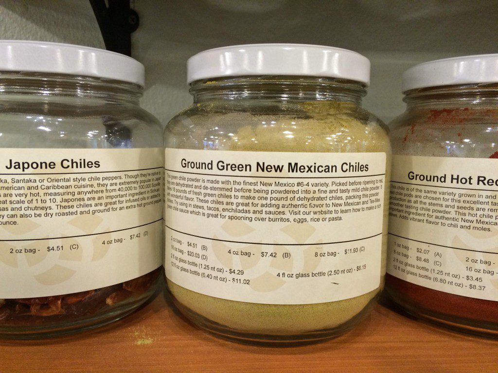 Three jars of spices on a shelf.