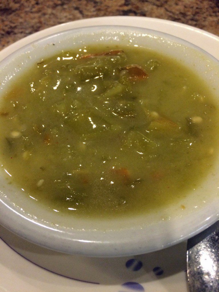 A bowl of green soup on a table.