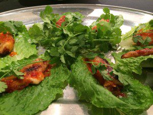 A plate of lettuce wraps with chicken on it.