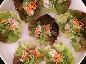 A plate of lettuce wraps topped with carrots and cranberries.