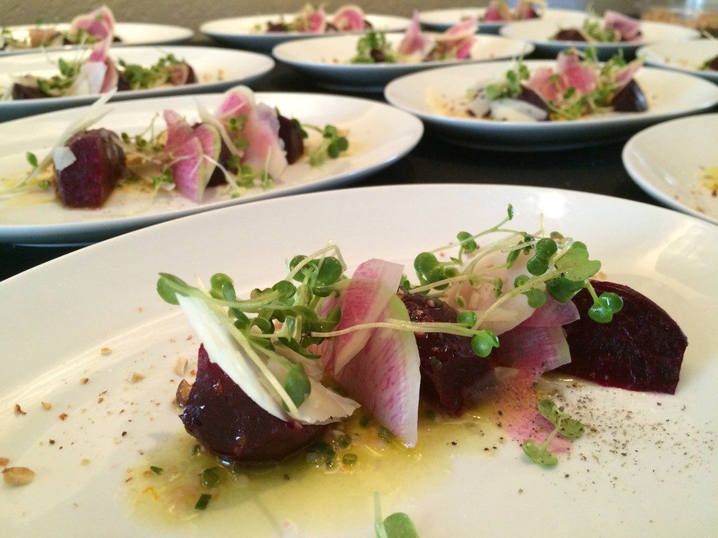 A plate of beets and sprouts on a table.